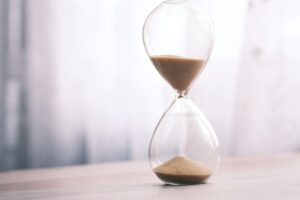 Minimalist hourglass filled with sand symbolizing time and patience, against a soft background.